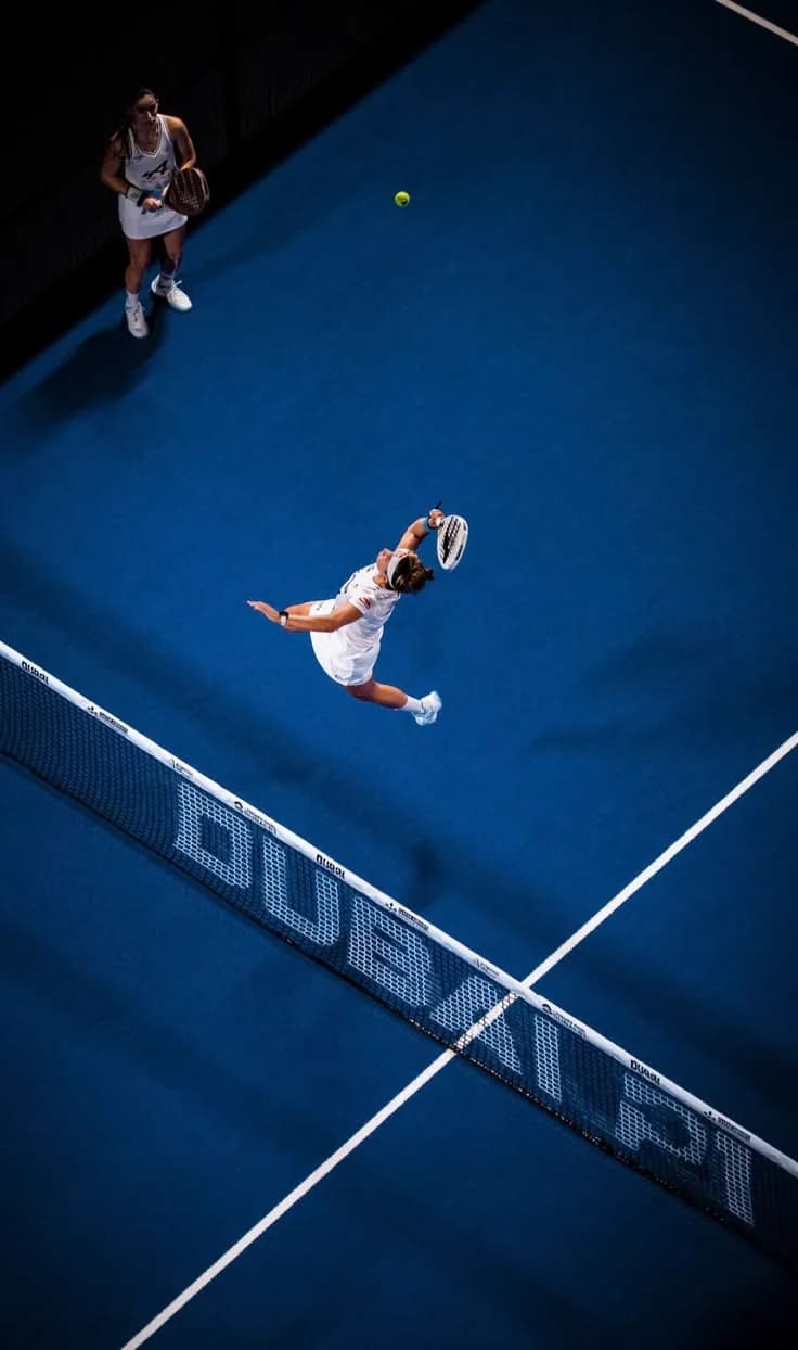 Deux joueuses de padel vues du dessus sur un terrain bleu.
